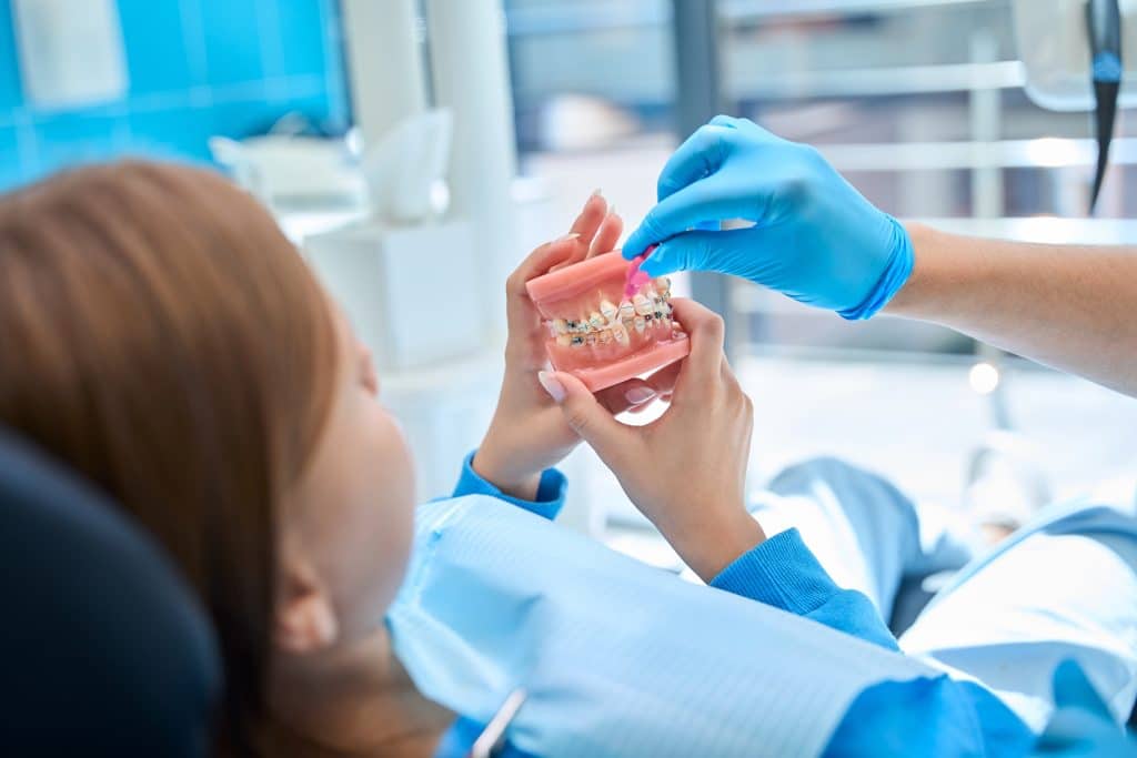 Orthodontist teaches child to care for oral cavity when wearing braces at an emergency orthodontist clinic in South Jordan